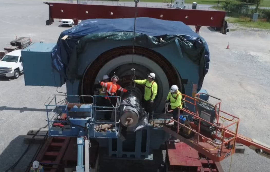 3 workers performing field services on a large electrical generator