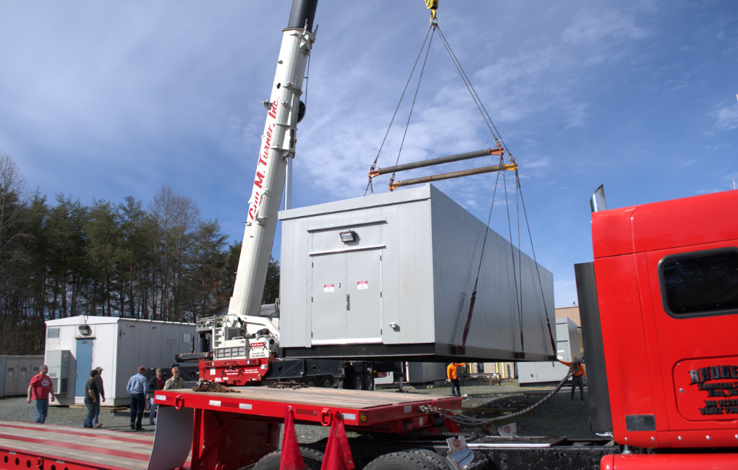Crane lifting a generator out of the bed of a truck trailer